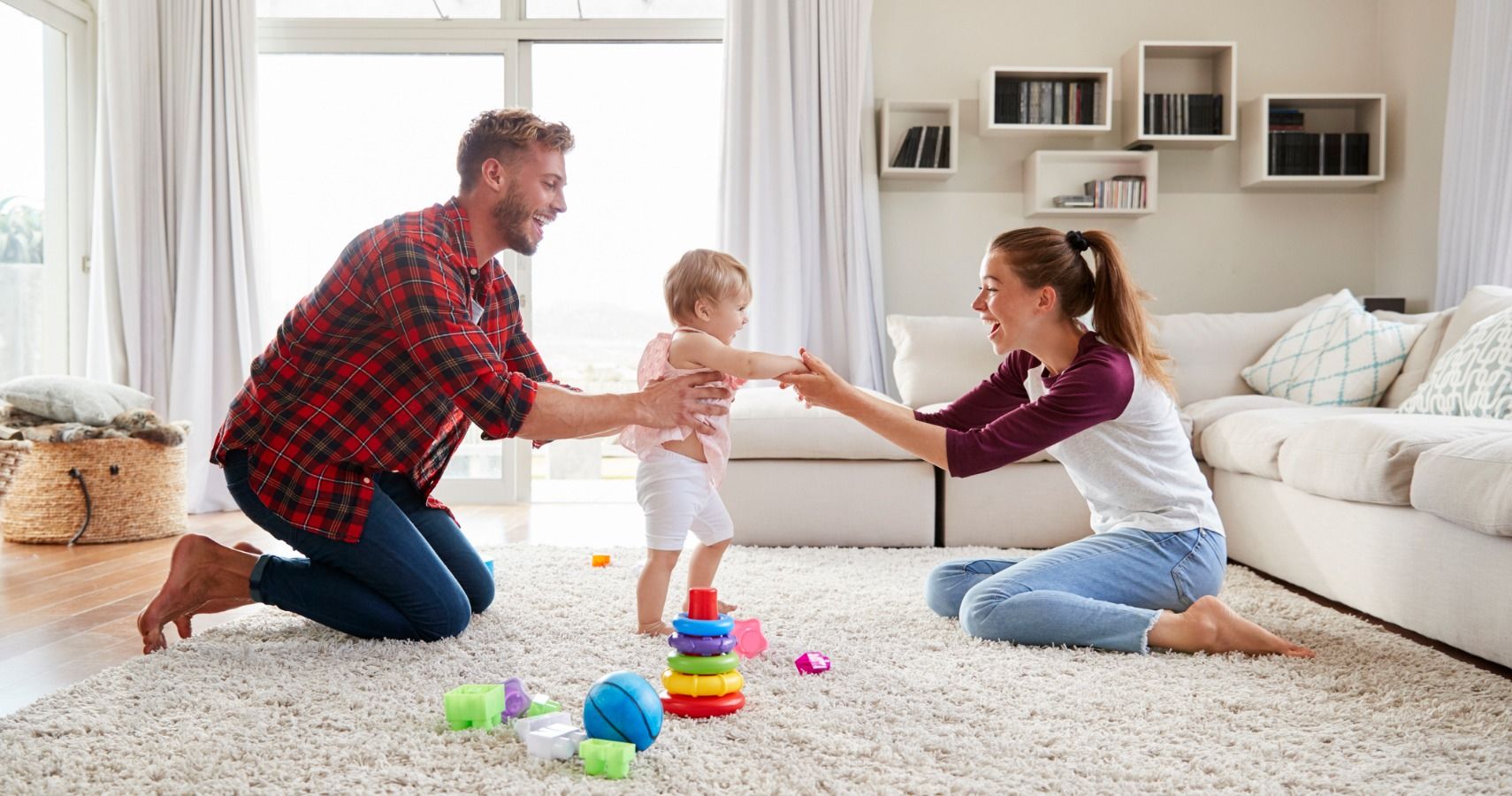toddler-girl-walking-from-dad-to-mum-in-sitting-room-picture-id947849414